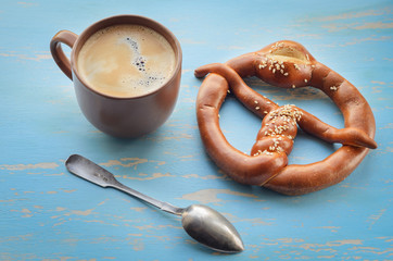 Cup of coffee with coffee beans and pretzel