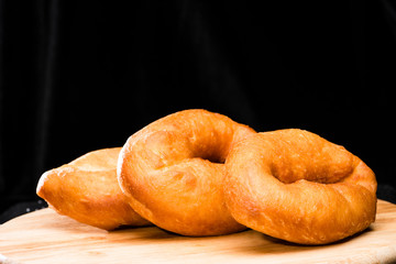 close-up of sweet fresh delicious donuts on round wooden board, dark background