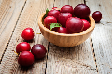 fresh plums in bowl on wooden background