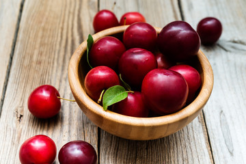 fresh plums in bowl on wooden background
