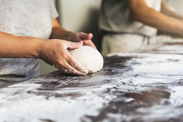 Baker preparing bread. Close up of hands kneading dough.