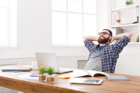 Young relaxed businessman with laptop in modern white office