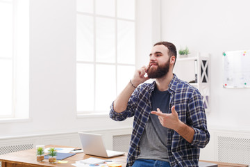 Fototapeta premium Young smiled businessman has a mobile talk in modern white office