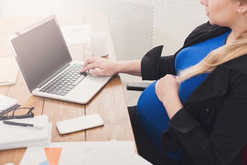 Pregnant woman working on laptop with blank screen