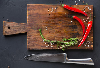 Wooden desk with spices and chilli on dark background