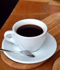 Glass cup of a black coffee on a wooden table.
