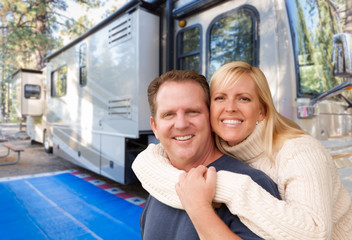 Happy Caucasian Couple In Front of Their Beautiful RV At The Campground.