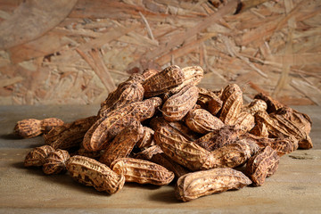 Pile raw peanuts in shell on wooden background