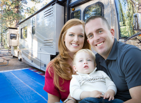 Happy Young Military Family In Front of Their Beautiful RV At The Campground.