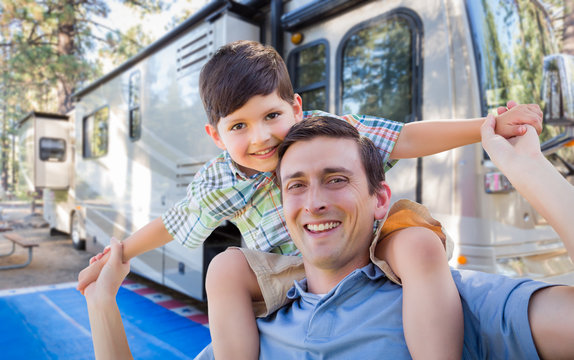 Happy Young Caucasian Father and Son In Front of Their Beautiful RV At The Campground.