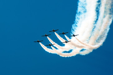 Fighter flies in the smoke in the blue sky aerobatics - obrazy, fototapety, plakaty