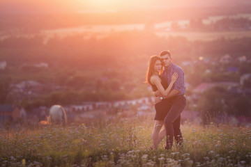 man and girl in love romantic lovers kissing, hugging at sunset, sunrise on the background of mountains and fog, sun, clouds in fiery red, orange colors