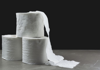 Close-up image stack of toilet papers roll on the table with dark background.