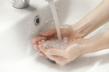 Hands cupping running water under bathroom sink faucet, hygiene concept