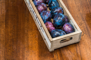 fresh plums with waterdrops on it in a wooden box