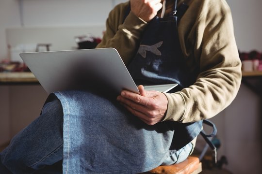 Craftsman using laptop while sitting in workshop