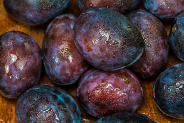 fresh plums with waterdrops on it in a wooden box