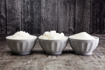 Bowl with white sand and lump sugar on grey background