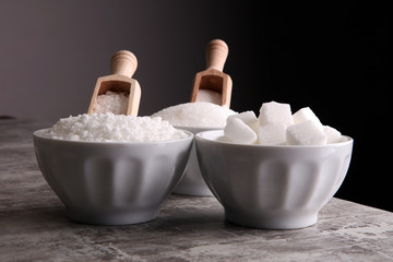 Bowl with white sand and lump sugar on grey background