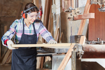 Frau als Lehrling sägt Holz in Schreinerei
