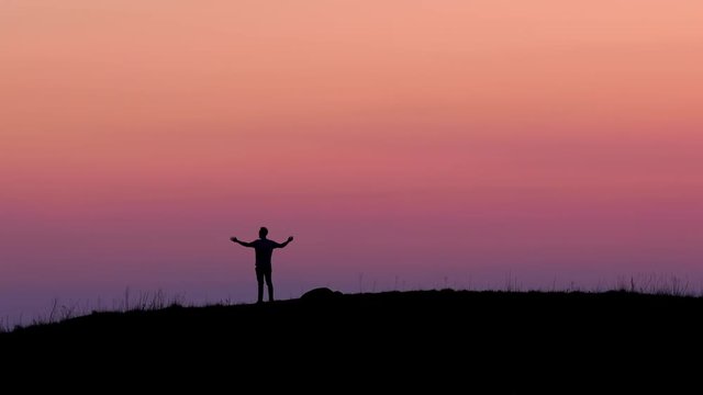 Man on top of hill raising arms. Silhouette. Success.