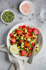Avocado, tomato, black  bean, corn and bell pepper salad in white bowl