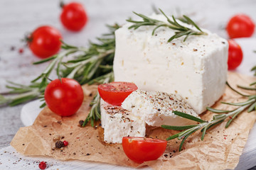 Fototapeta na wymiar Fresh feta cheese with rosemary on white wooden serving board