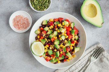 Avocado, black  bean, corn and bell pepper salad in white bowl