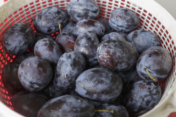 Vegan food. Fresh plum in a dish, isolated on white background