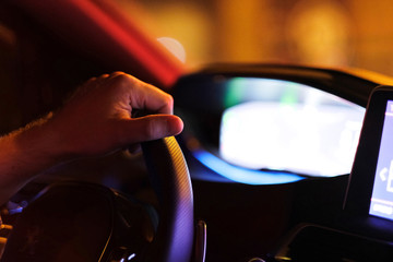 The driver's hand on the steering wheel in the car's interior