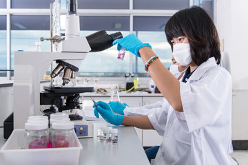 Women Scientist checking test sample with microscope