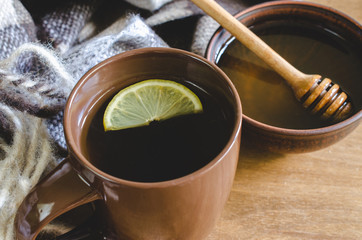A cup of hot tea with lemon, honey and plaid.