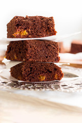 Stack three square pieces of homemade chocolate brownies. Dark Chocolate cake with orange. Light background. Close up.