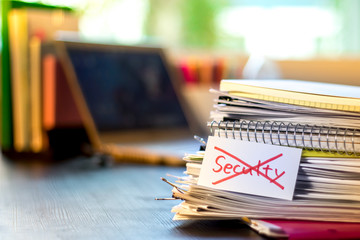 Seculty; Stack of Documents and Laptop at working Desk.
