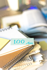 100 Percent; Stack of Documents and Laptop at working Desk.