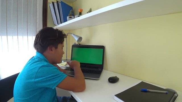Young boy with green screen laptop monitor