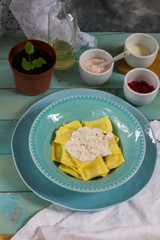 Ravioli with mushrooms and with bacon and sour cream sauce. Blue wooden table, blue plates.