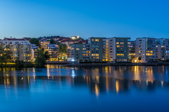 En vacker sommarnatt ser vi  belysningen i bostadshus p&aring; Lilla Essingens speglas i vattnet