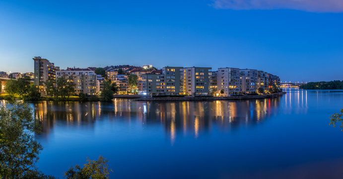 En vacker sommarnatt ser vi  belysningen i bostadshus p&aring; Lilla Essingens speglas i vattnet