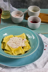 Ravioli with mushrooms and with bacon and sour cream sauce. Blue wooden table, blue plates.