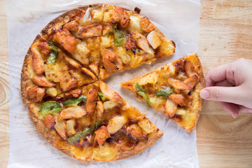 hand pickup a piece of BBQ chicken supreme pizza