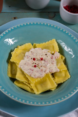 Ravioli with mushrooms and with bacon and sour cream sauce. Blue wooden table, blue plates.