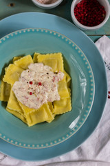 Ravioli with mushrooms and with bacon and sour cream sauce. Blue wooden table, blue plates.