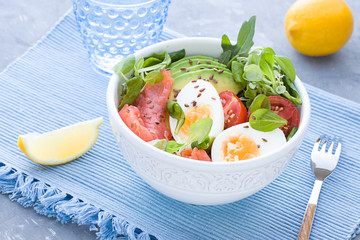Healthy salad with avocado, corn salad, smoky salmon, eggs and tomatoes for breakfast. Close up