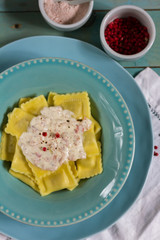 Ravioli with mushrooms and with bacon and sour cream sauce. Blue wooden table, blue plates.