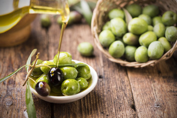 Bottle pouring virgin olive oil in a bowl close up