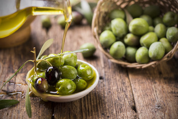 Bottle pouring virgin olive oil in a bowl close up