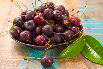 Fresh ripe black cherries in a bowl on a wooden background
