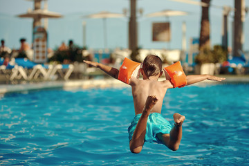 Caucasian boy having fun jumping into the pool. - 170489325