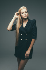 Beautiful female model in black dress on gray background